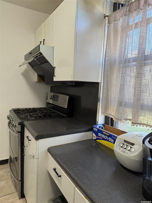 kitchen with gas range, light tile patterned floors, ventilation hood, and white cabinetry