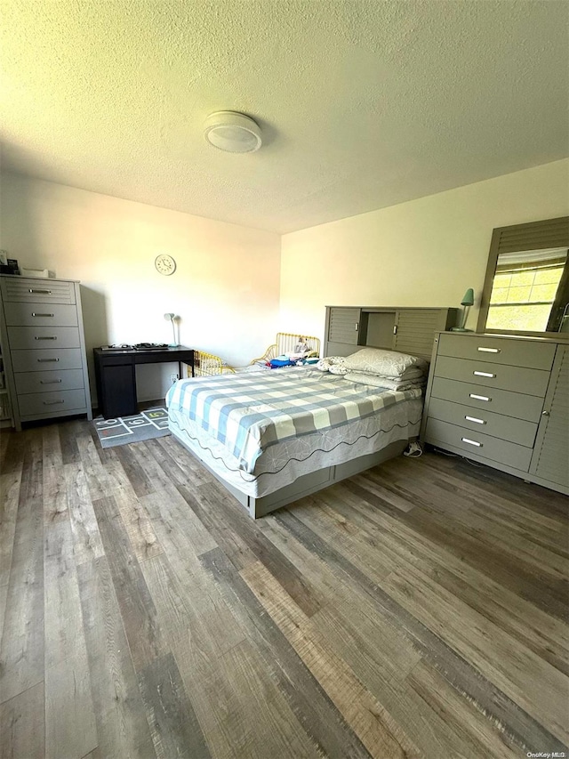 bedroom with dark hardwood / wood-style floors and a textured ceiling