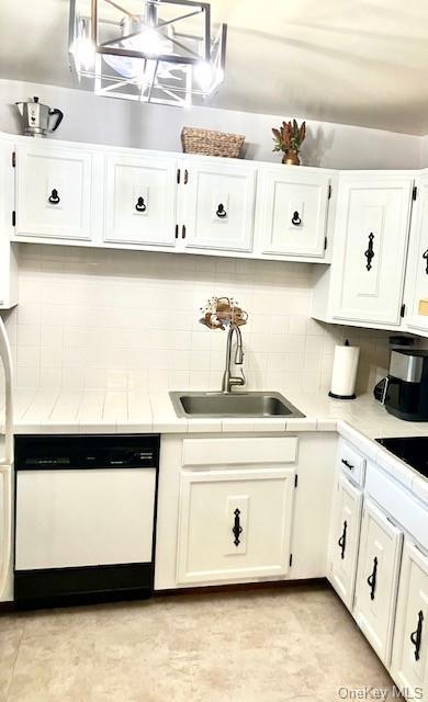 kitchen featuring sink, dishwasher, white cabinets, and tasteful backsplash