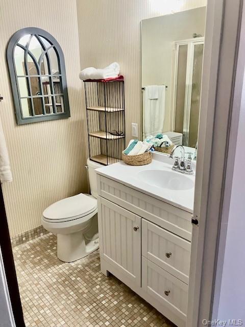 bathroom with an enclosed shower, vanity, toilet, and tile patterned flooring