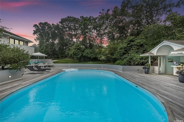 pool at dusk featuring a wooden deck