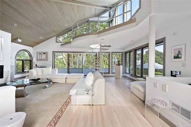 living room with plenty of natural light, high vaulted ceiling, and light wood-type flooring