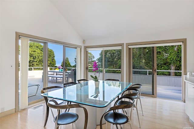 dining space featuring high vaulted ceiling and light hardwood / wood-style floors