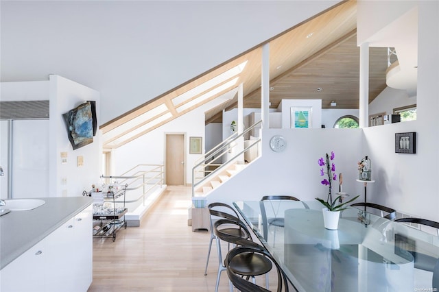 dining room with light hardwood / wood-style floors and high vaulted ceiling