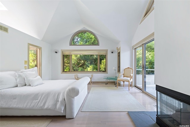 bedroom with multiple windows, light hardwood / wood-style flooring, high vaulted ceiling, and access to exterior