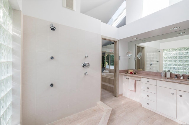 bathroom featuring a tile shower, vanity, and high vaulted ceiling