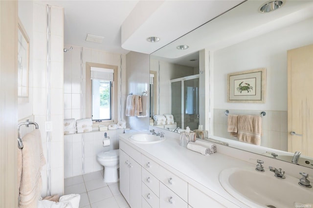 bathroom featuring tile patterned flooring, an enclosed shower, toilet, vanity, and tile walls