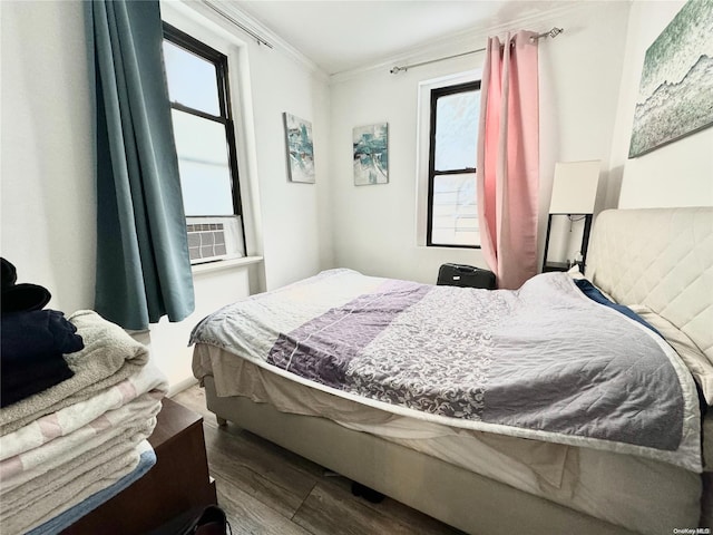 bedroom with cooling unit, wood-type flooring, and crown molding