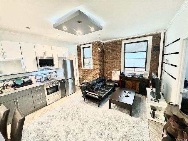 kitchen featuring white cabinetry, stainless steel appliances, tasteful backsplash, brick wall, and light wood-type flooring