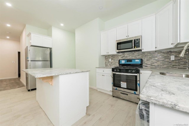 kitchen with a center island, sink, stainless steel appliances, light hardwood / wood-style flooring, and white cabinets