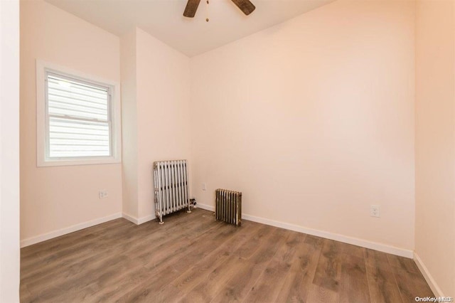 unfurnished room featuring ceiling fan, radiator heating unit, and hardwood / wood-style floors