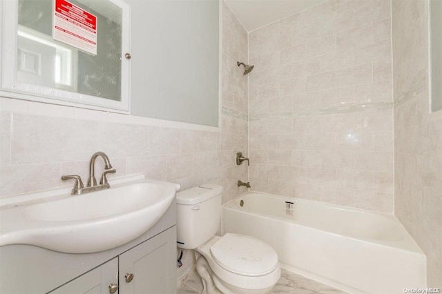 full bathroom with tiled shower / bath combo, toilet, tile walls, and vanity