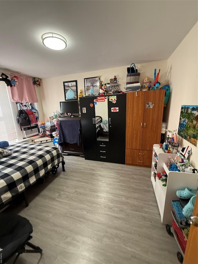 bedroom featuring light wood-style flooring and freestanding refrigerator