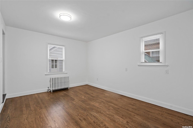 spare room featuring radiator, plenty of natural light, and dark hardwood / wood-style flooring