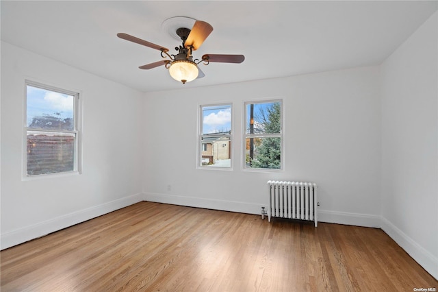 unfurnished room with radiator, ceiling fan, a healthy amount of sunlight, and light hardwood / wood-style floors