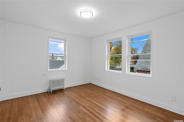 empty room with radiator heating unit and hardwood / wood-style flooring