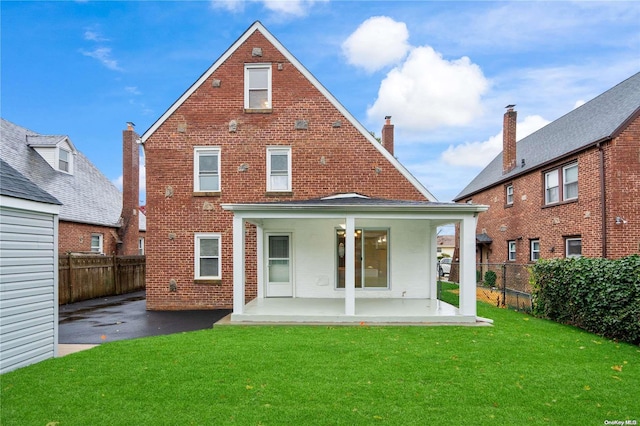 rear view of property featuring a lawn and a patio