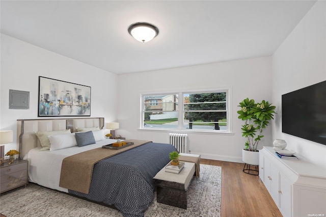 bedroom featuring radiator heating unit and light wood-type flooring