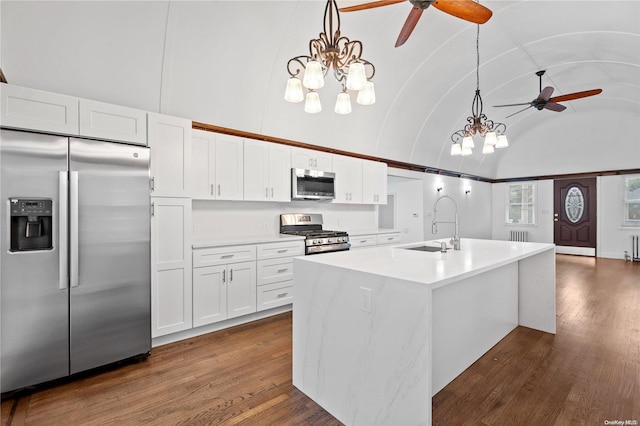 kitchen with pendant lighting, a kitchen island with sink, stainless steel appliances, white cabinets, and vaulted ceiling