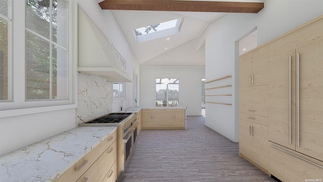 kitchen featuring light brown cabinets, high end stainless steel range oven, vaulted ceiling with skylight, exhaust hood, and hardwood / wood-style flooring