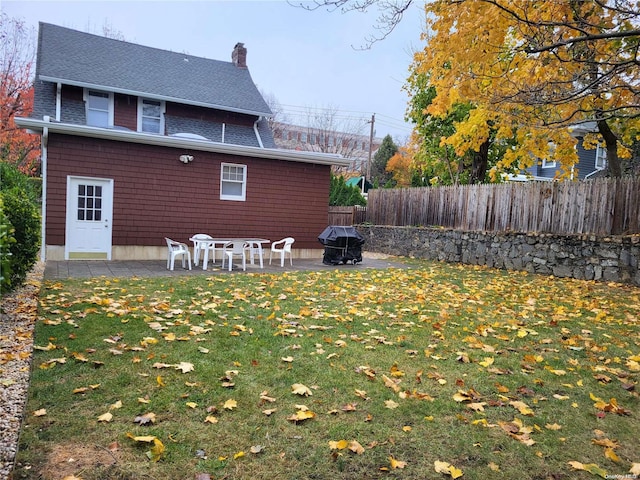 back of house featuring a yard, a patio, and a fire pit