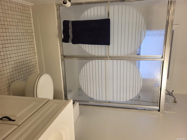 bathroom with a shower with door, tile walls, and toilet