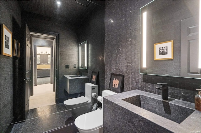 bathroom featuring toilet, tile walls, and sink