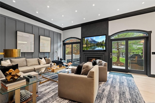 living room featuring crown molding, a large fireplace, and light hardwood / wood-style floors