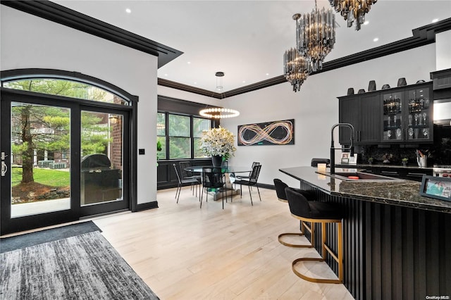 interior space featuring light wood-type flooring, tasteful backsplash, ornamental molding, decorative light fixtures, and a chandelier