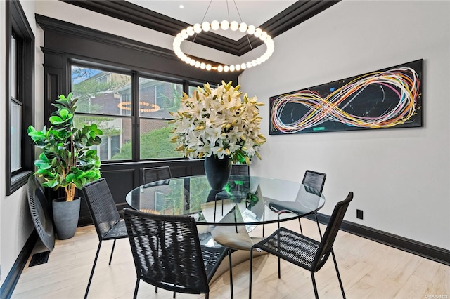 dining space featuring light wood-type flooring and crown molding