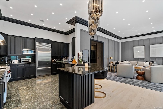 kitchen featuring sink, a center island, stainless steel appliances, a kitchen breakfast bar, and dark stone countertops