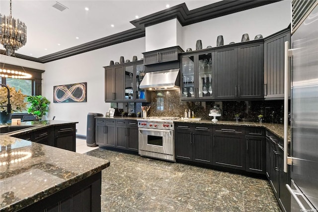 kitchen featuring decorative backsplash, ornamental molding, wall chimney exhaust hood, premium appliances, and decorative light fixtures