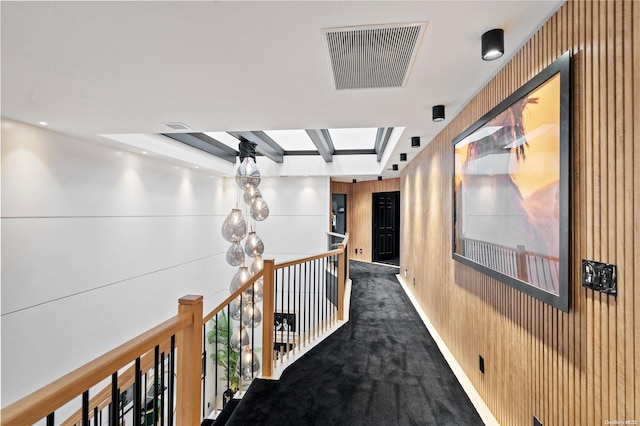 hallway featuring dark carpet and wooden walls