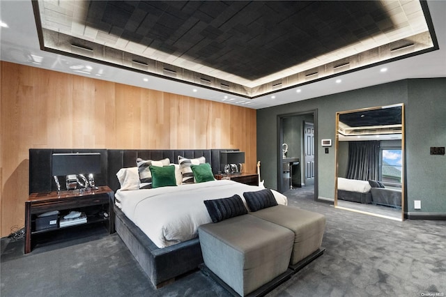 bedroom with a tray ceiling, wood walls, and carpet flooring