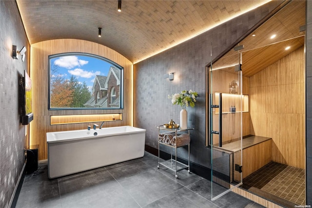 bathroom with concrete flooring, a tub, and vaulted ceiling