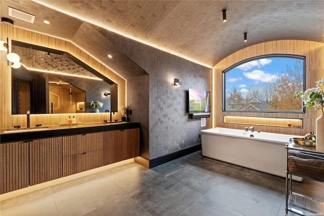 bathroom with vanity, wood walls, a bath, and vaulted ceiling