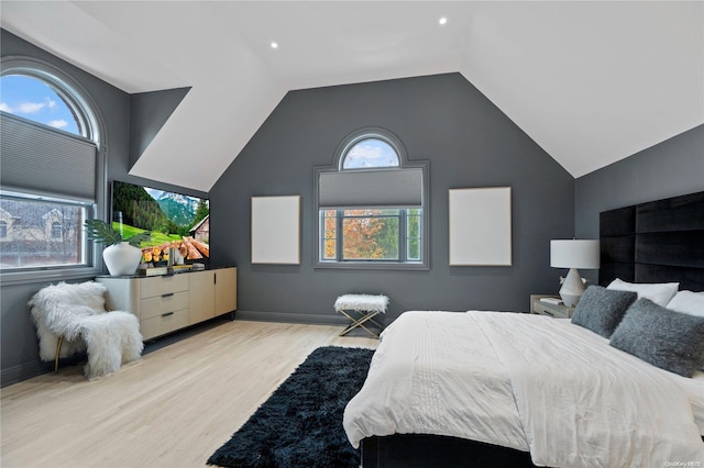 bedroom featuring light hardwood / wood-style floors, multiple windows, and lofted ceiling