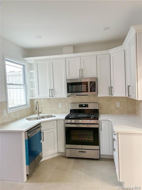 kitchen featuring appliances with stainless steel finishes, light tile patterned floors, white cabinetry, and sink