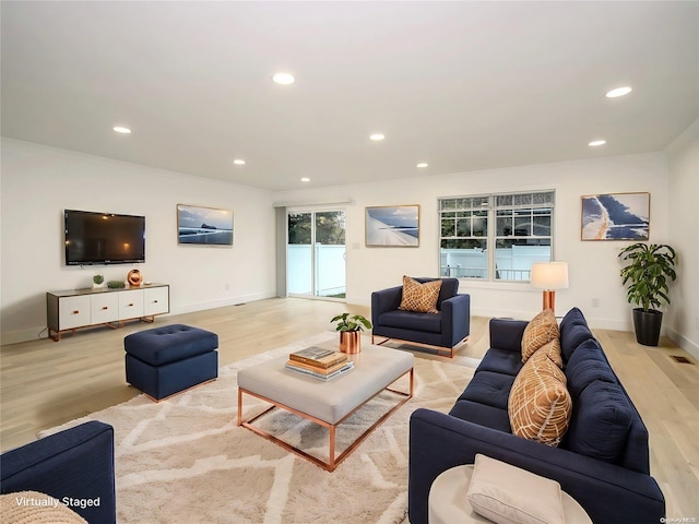 living room featuring light wood-type flooring and ornamental molding