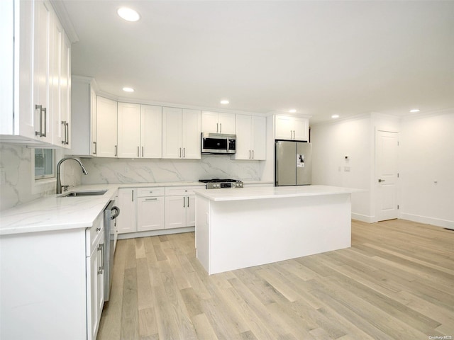 kitchen featuring appliances with stainless steel finishes, light wood-type flooring, sink, a center island, and white cabinetry