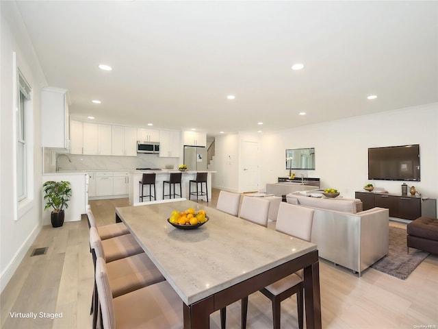 dining space with light hardwood / wood-style flooring and sink