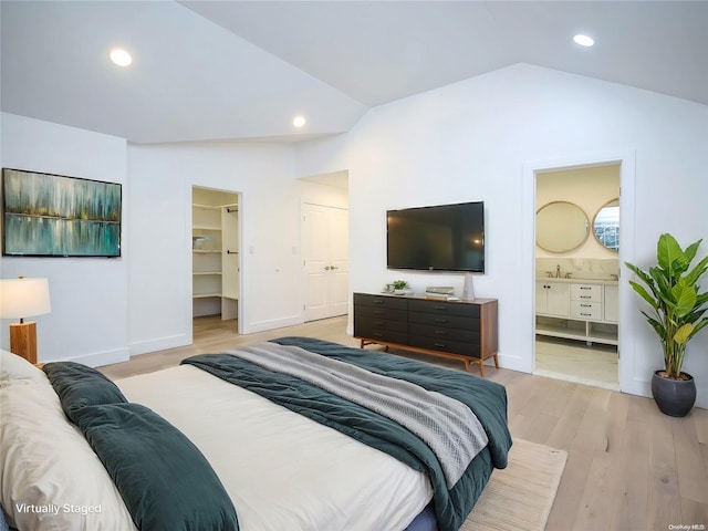 bedroom with ensuite bath, vaulted ceiling, a spacious closet, light hardwood / wood-style floors, and a closet