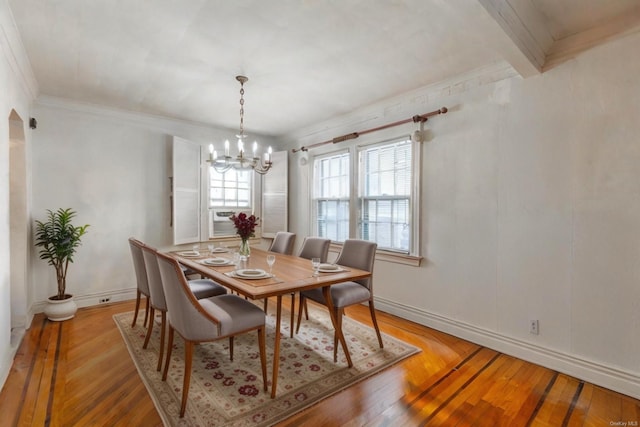 dining space with beamed ceiling, a notable chandelier, ornamental molding, and light hardwood / wood-style flooring