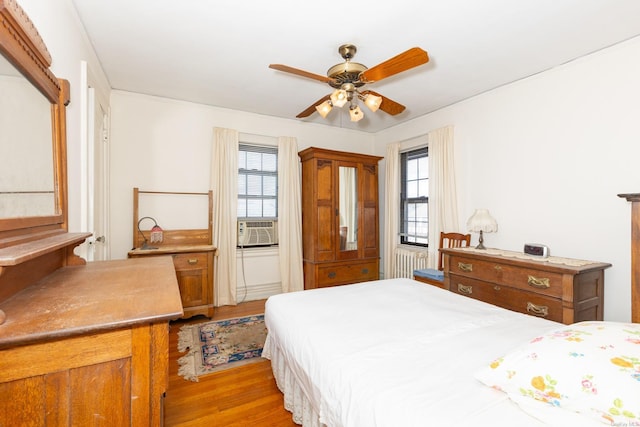 bedroom with cooling unit, ceiling fan, light hardwood / wood-style floors, and multiple windows