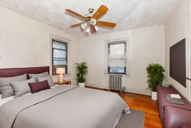 bedroom with hardwood / wood-style flooring, ceiling fan, and radiator heating unit