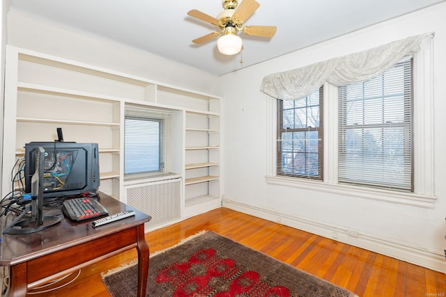 office space featuring hardwood / wood-style floors, ceiling fan, and radiator