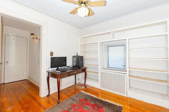 home office featuring hardwood / wood-style floors, ceiling fan, and radiator heating unit