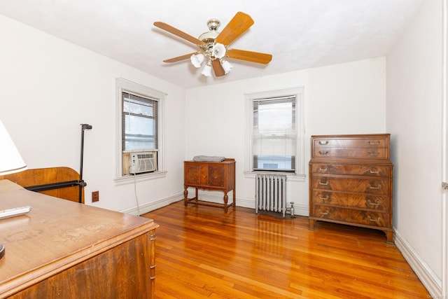 office space with radiator heating unit, ceiling fan, plenty of natural light, and wood-type flooring