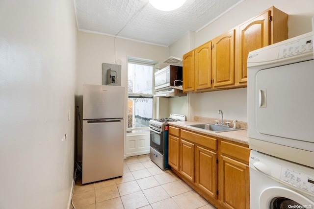 kitchen featuring sink, stainless steel gas range, white fridge, stacked washer / drying machine, and light tile patterned flooring