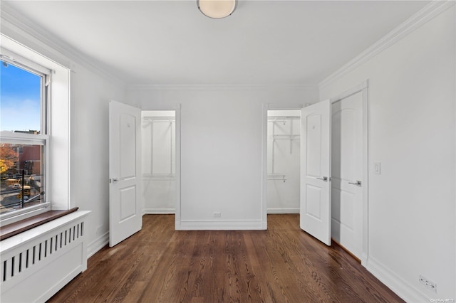 unfurnished bedroom featuring radiator, a spacious closet, ornamental molding, dark hardwood / wood-style flooring, and a closet